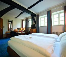 Bett uns Sitzecke mit Fachwerkbalken im Zimmer im Hotel Alt Warburg