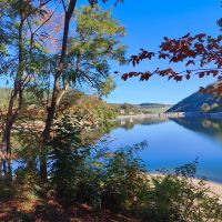 Blick auf den Diemelsee in der Herbstsonne, ganz hinten die Sperrmauer, vorne B&auml;ume
